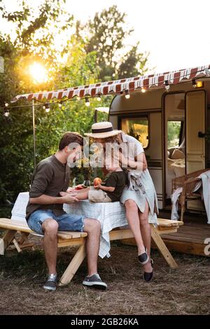 Famille active dans un camp de pique-nique en camping-car en forêt d'été. Les parents apprécient les vacances en caravane avec leur fils Banque D'Images