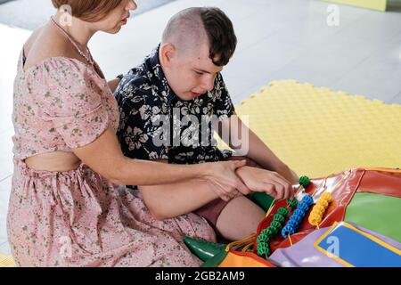 Les enfants ayant un handicap se font une activité sensorielle avec des jouets, des balles, des petits objets, un garçon souffrant de paralysie cérébrale jouant à un jeu apaisant, s'entraîner à de fines aptitudes motrices Banque D'Images