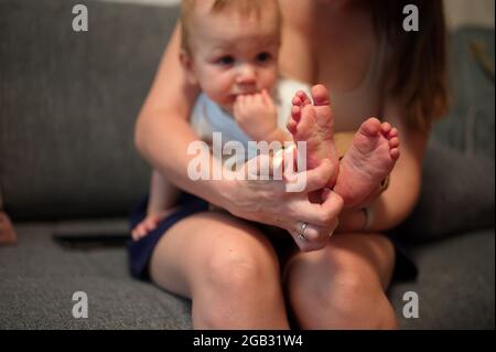 Mère tenant un petit garçon doux avec ses pieds en premier plan Banque D'Images