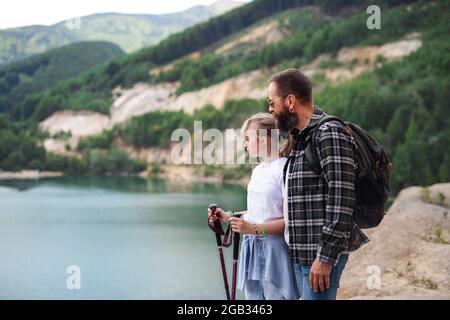 Bonne fille de préadolescence avec le père en randonnée sur les vacances d'été, regardant le paysage du lac. Banque D'Images