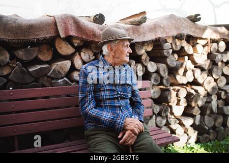 Portrait d'un homme âgé assis sur un banc à l'extérieur dans le jardin, reposant. Banque D'Images