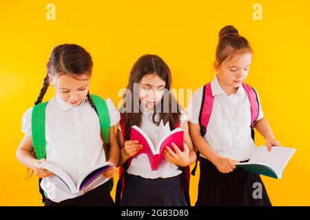 Les petites écolières lisent les livres sur fond jaune Banque D'Images