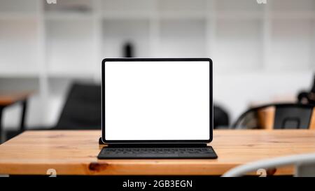 Tablette d'ordinateur avec écran blanc vierge sur un espace de travail en bois Banque D'Images