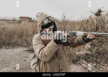 garçon errant. garçon avec une arme. garçon va dans un bâtiment abandonné. garçon se tient devant un bâtiment. Après l'apocalypse. Homme voyageant à pied dans un post- Banque D'Images