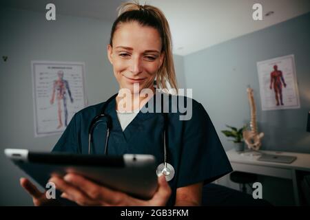 Femme caucasienne médecin travaillant en clinique tenant une tablette numérique Banque D'Images