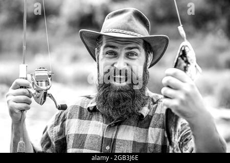 Homme tenant un poisson de truite. Pêche. Pêcheur à la ligne avec trophée de pêche. Pêcheur et truite. Fonds de pêche. Noir et blanc Banque D'Images