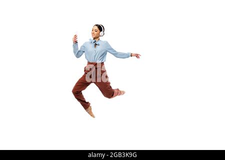 Ballerine souriante dans un casque utilisant un smartphone tout en sautant isolé sur blanc Banque D'Images