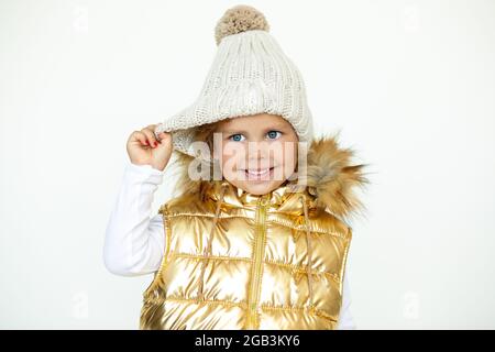 Mode pour enfants. Photo d'une petite fille en laine naturelle chaude chapeau et gilet en or enfants avec capuche, gilet, photo Banque D'Images