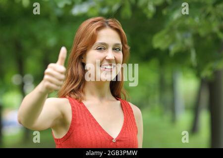 Bonne femme en faisant un geste pour regarder un appareil photo dans un parc Banque D'Images