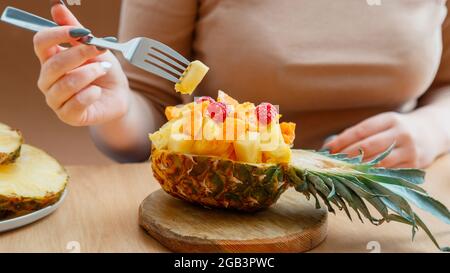 Salade de fruits dans un demi-bol d'ananas. Salade de fruits tropicaux savoureuse manger femme au café. Dessert de fruits à couper le plat à l'ananas. Long Banque D'Images