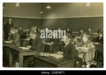 Carte postale originale du début des années 1900, datant de la première Guerre mondiale, de jeunes hommes assis à leur bureau dans une salle de classe, certains en uniforme, du studio de J&G Taylor, 631 Green Lanes, North London, Royaume-Uni vers 1914-1918 Banque D'Images