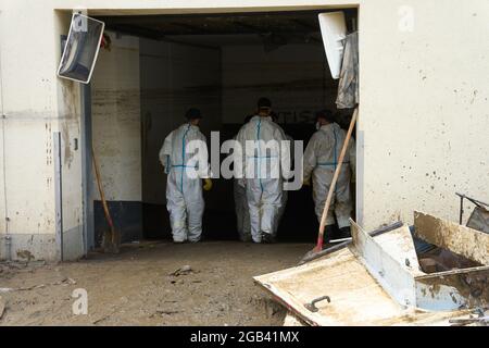 02 août 2021, Rhénanie-Palatinat, Bad Neuenahr-Ahrweiler : les aides THW en vêtements de protection entrent dans le sous-sol d'un bâtiment résidentiel. Deux semaines et demie après la catastrophe des inondations, le travail de nettoyage est en plein essor. Photo: Thomas Frey/dpa Banque D'Images