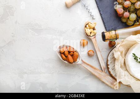 Noix de cajou et d'amandes en cuillères en bois comme amuse-gueules ensemble de collation pour le vin et le fromage sur pierre Table gris clair avec espace pour le texte. Collations au vin rustique Banque D'Images