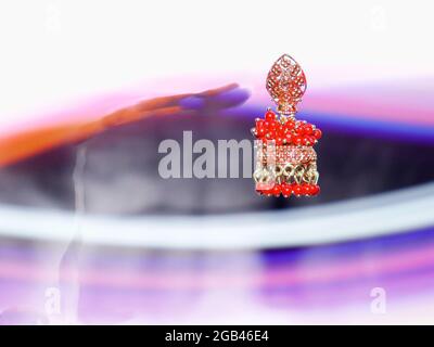 Boucles d'oreilles de couleur rouge pour femmes présentées dans l'air avec fond brillant à effet de lumière, image de présentation de produit commercial. Banque D'Images