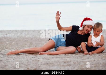 Mère et fils célébrant la Saint-Sylvestre ou Noël sur la plage, au bord de la mer. Concept de vacances. Photo de haute qualité Banque D'Images