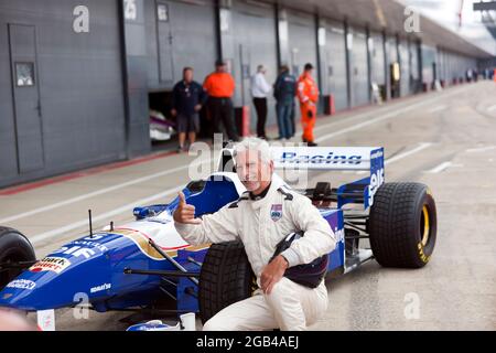 Damon Hill posant à côté de son Championnat du monde gagnant Williams FW18 Formule 1 car, après avoir effectué plusieurs tours de démonstration à grande vitesse du circuit, au Silverstone Classic 2021 Banque D'Images