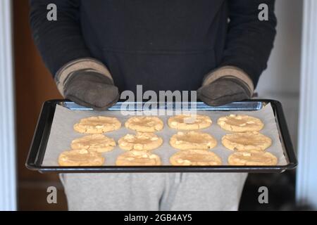 Photo d'un homme tenant une assiette remplie de petits gâteaux ronds fraîchement cuits Banque D'Images