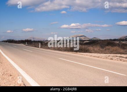 La route asphaltée sur le fond des montagnes.Vue en paysage perspective de route avec des nuages blancs sur ciel bleu.En voiture Banque D'Images