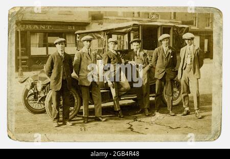 Carte postale originale du début des années 1920, de jeunes hommes de la classe ouvrière à côté d'une voiture classique avec des casquettes plates et des meilleurs costumes avec un pantalon à revers, peut-être une fête de mariage, du studio de Harold Whitworth, Salisbury, Royaume-Uni Banque D'Images