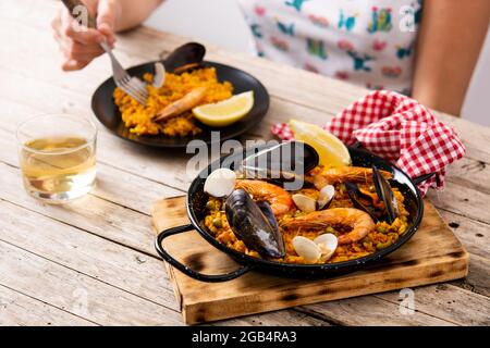Femme mangeant de la paella espagnole de fruits de mer sur une table en bois Banque D'Images