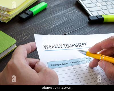 Homme remplissant la feuille de temps hebdomadaire de l'employé dans le bureau. Banque D'Images