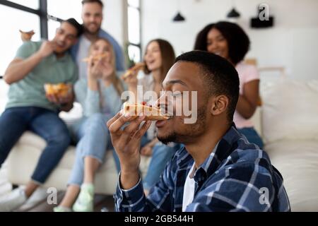 Cool noir gars manger de la pizza sur la fête nationale avec ses amis multiethniques, copier l'espace Banque D'Images