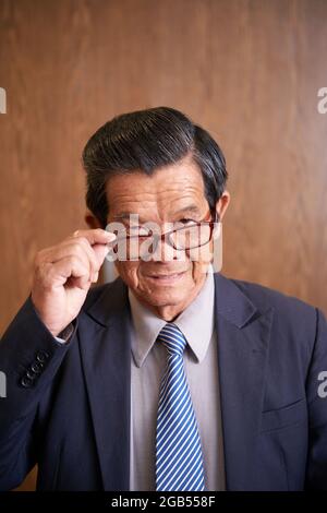 Portrait d'un homme d'affaires souriant prenant des lunettes et regardant l'appareil photo Banque D'Images
