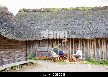 Des acteurs habillés de vêtements viking d'âge moyen et effectuant des activités quotidiennes des villageois viking dans le village de Viking Haithabu. Prise à Busdorf, Allemagne Banque D'Images