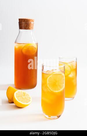 Deux verres et un pichet de thé glacé fraîchement préparé au citron sur fond blanc. Banque D'Images