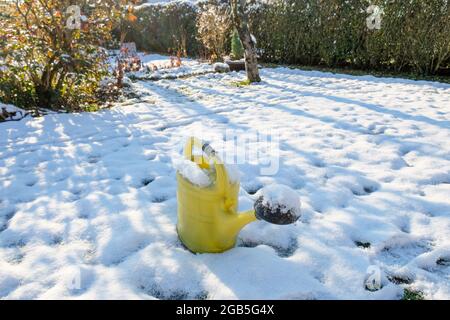 Un arrosoir jaune peut se mettre dans le jardin enneigé en hiver Banque D'Images