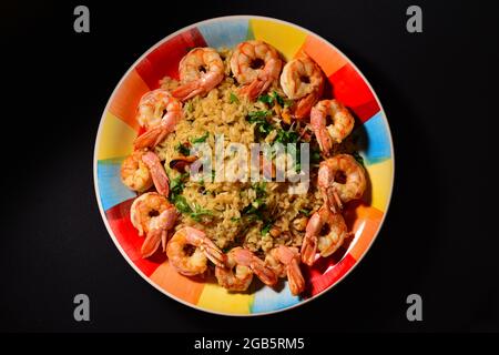 Plat traditionnel italien ,,risotto aux fruits de mer,, , riz aux crevettes , moules , ail , vin blanc , persil sur une belle assiette colorée. Banque D'Images