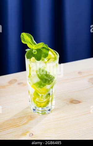 Cocktail Mojito sur fond de bois. Cocktail mojito d'été dans un grand verre. Boisson rafraîchissante au citron vert, à la menthe et à la glace. Boisson tendance Banque D'Images
