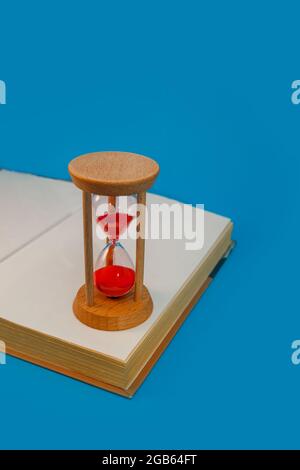 hourglass et livre sur fond bleu Banque D'Images