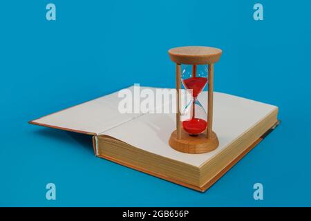 hourglass et livre sur fond bleu Banque D'Images