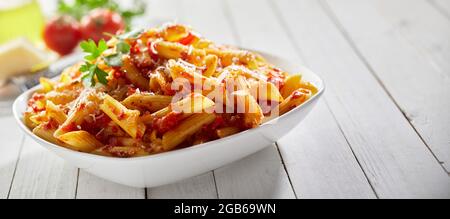 Délicieux penne arrabiata avec persil servi dans un bol sur une table de bois pendant le déjeuner au restaurant Banque D'Images