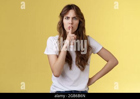 Fermez la bouche sans parler pendant le concert. Sérieuse-look strict mécontente adulte sœur demande assis silencieux hessing tenir index enfoncé lèvres pressées Banque D'Images