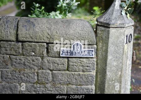 Un mur en pierre et pilier hexagonal en pierre avec la maison numéro 10 et le titre de la propriété l'ancien Vicarage Banque D'Images