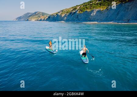 28 mai 2021. Anapa, Russie. Couple sur stand-up paddle board à la mer bleue avec des rochers. Les gens sur Red paddle sup bord dans la mer transparente. Vue aérienne Banque D'Images