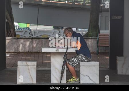 Un Chinois lit le papier dans un stand à Hong Kong Banque D'Images