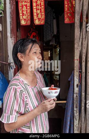 Une dame chinoise dans son magasin de porte aime quelques nouilles Banque D'Images