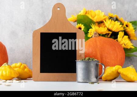 Un tableau de craie vide entouré de citrouilles et de tournesols. Composition d'automne. Bonne action de grâces. Copier l'espace. Banque D'Images