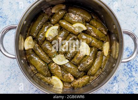 Feuilles de vigne fourrées traditionnelles bulgares faites maison avec du riz et garnies de tomates fraîches, de citron et de sauce de yaourt Banque D'Images