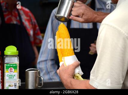 Un homme achète deux épis de maïs torréfié sur l'épi dans un stand de nourriture à Santa Fe, Nouveau-Mexique. Banque D'Images