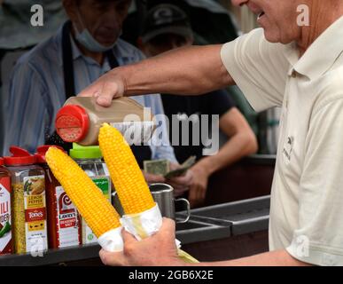 Un homme achète deux épis de maïs torréfié sur l'épi dans un stand de nourriture à Santa Fe, Nouveau-Mexique. Banque D'Images
