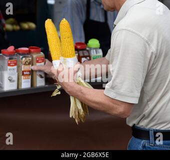 Un homme achète deux épis de maïs torréfié sur l'épi dans un stand de nourriture à Santa Fe, Nouveau-Mexique. Banque D'Images