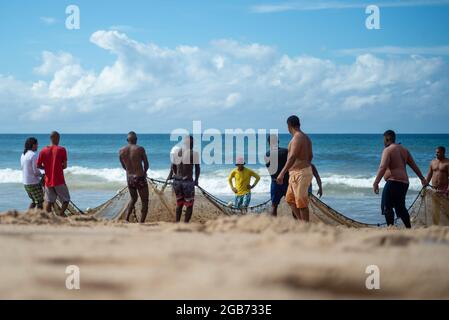 Salvador, Bahia, Brésil - 23 mai 2021 : pêcheurs tirant le filet de pêche de la mer avec des poissons à l'intérieur. Plage de Boca do Rio à Salvador. Banque D'Images