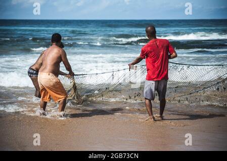 Salvador, Bahia, Brésil - 23 mai 2021 : pêcheurs tirant le filet de pêche de la mer avec des poissons à l'intérieur. Plage de Boca do Rio à Salvador. Banque D'Images