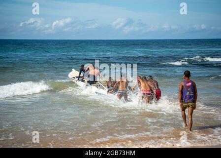 Salvador, Bahia, Brésil - 23 mai 2021 : les pêcheurs tirent leur canot de pêche dans la mer. Banque D'Images