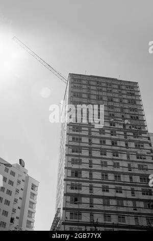 Photo en noir et blanc d'un immeuble résidentiel de plusieurs étages en construction et d'une grue sur fond de ciel bleu Banque D'Images