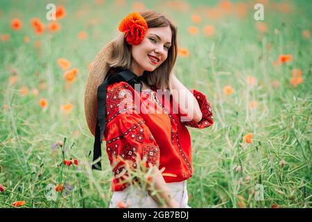 Jeune jolie femme dans le champ rouge des coquelicots. Nature, fleurs de fond. Lady en chemise ukrainienne brodée. Vêtements traditionnels nationaux. La culture Banque D'Images